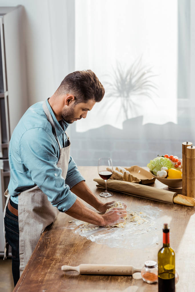 pohled z vysokého úhlu mladý muž v zástěře Příprava těsta v kuchyni - Fotografie, Obrázek