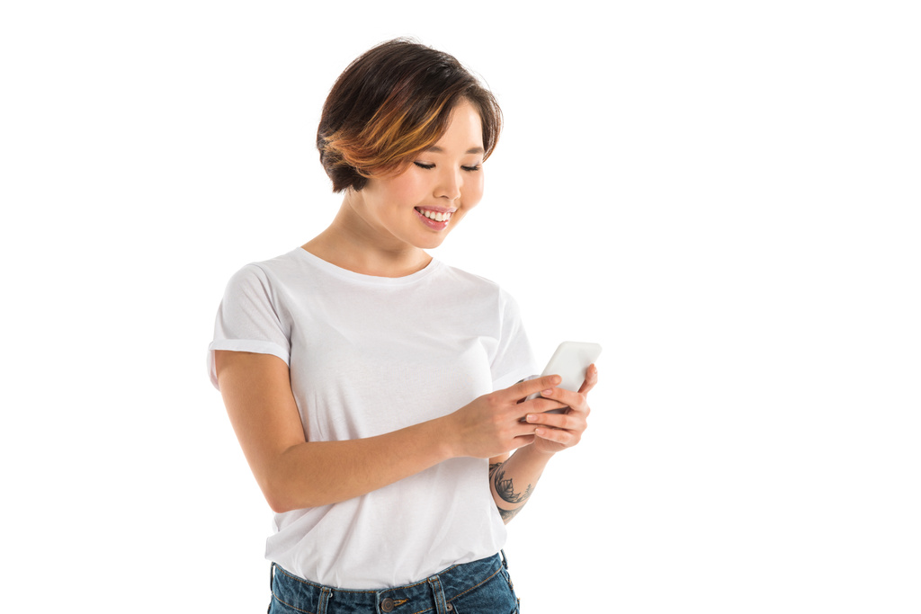 Mujer joven sonriente usando teléfono inteligente aislado en blanco
 - Foto, Imagen