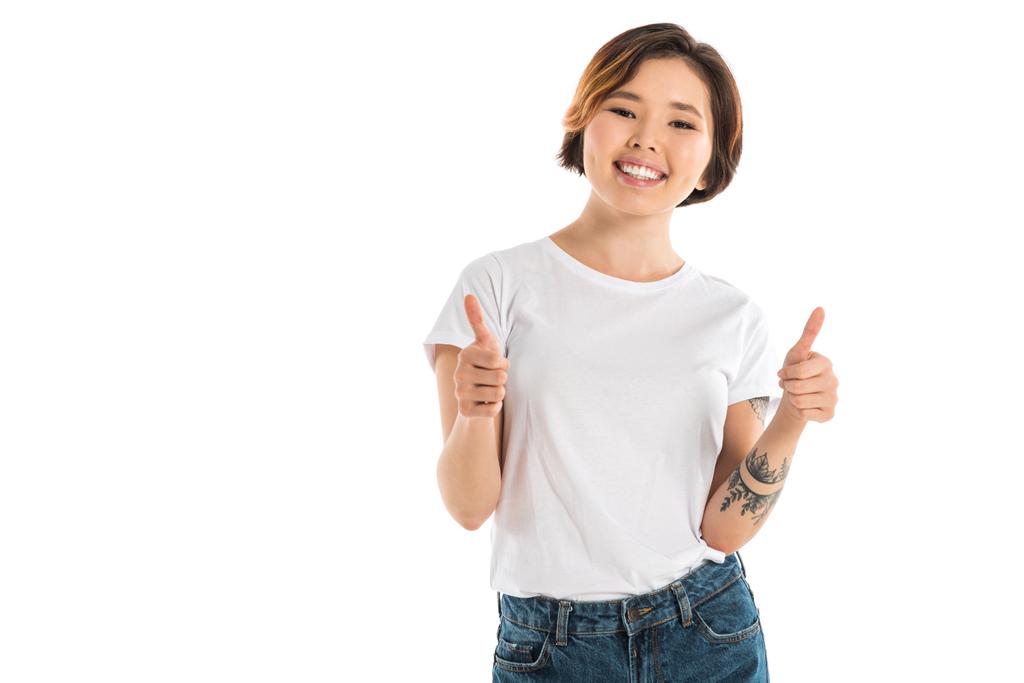 lachende jonge vrouw tonen duimschroef opwaarts tekenen en kijken naar camera geïsoleerd op wit - Foto, afbeelding
