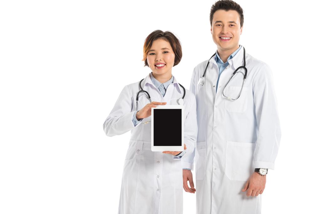 médecins féminins et masculins présentant tablette numérique avec écran blanc et regardant la caméra isolée sur blanc
 - Photo, image