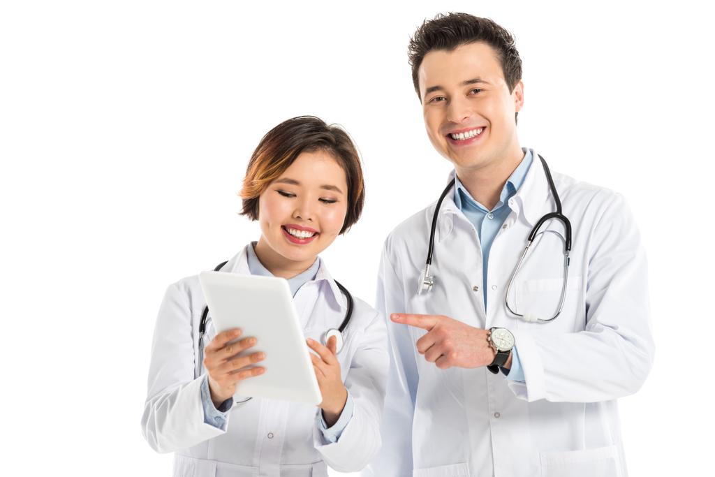 sonrientes doctores femeninos y masculinos usando tableta digital aislada en blanco
 - Foto, imagen