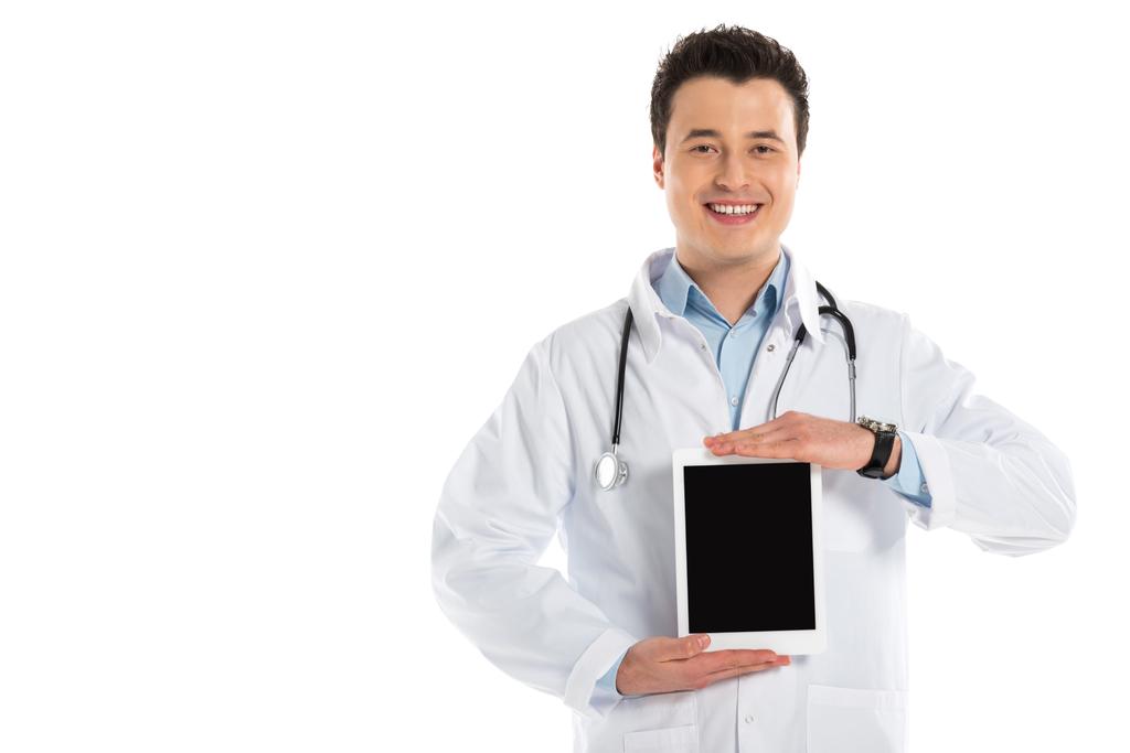 Lächelnder Arzt präsentiert digitales Tablet mit leerem Bildschirm isoliert auf weißem Hintergrund - Foto, Bild