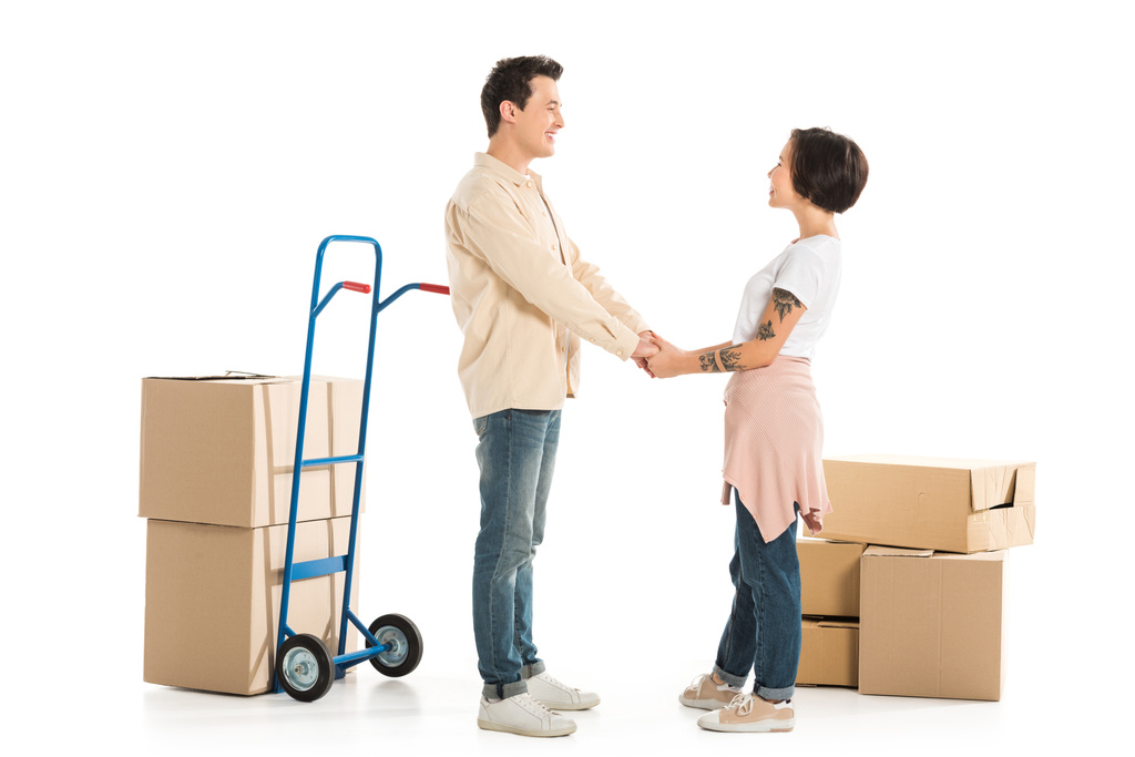 муж и жена держатся за руки с картонными коробками на заднем плане, переходя к новой концепции дома
 - Фото, изображение