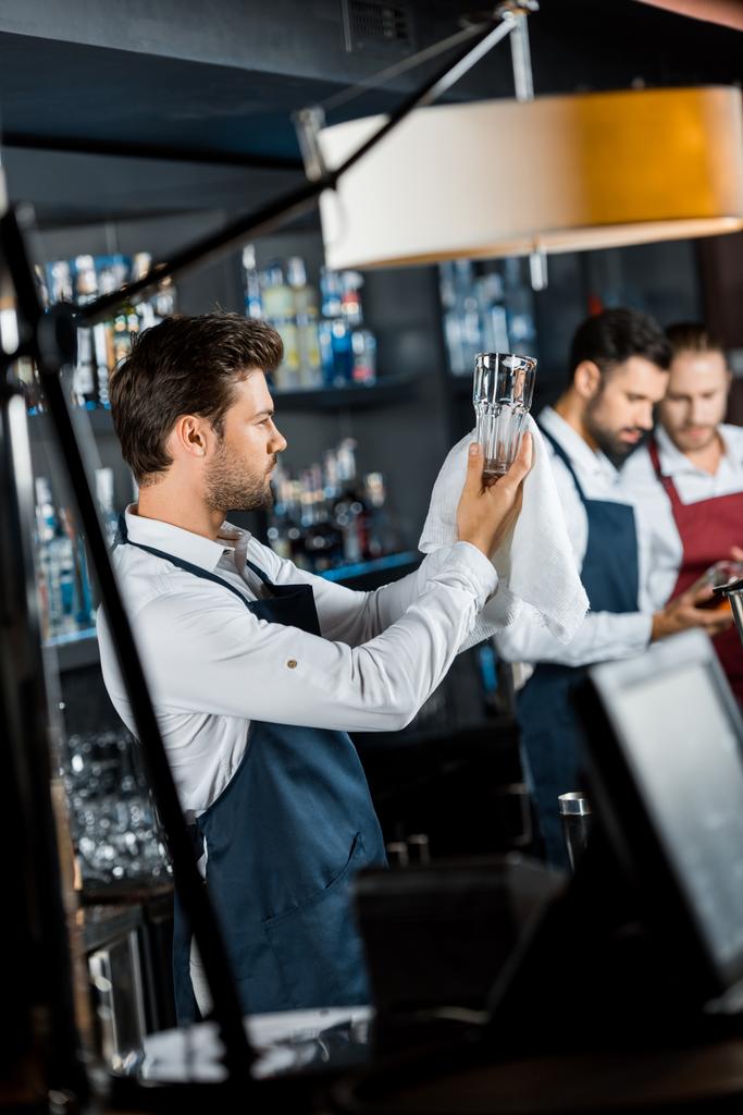 barman guapo mirando vidrio limpio en el lugar de trabajo
 - Foto, Imagen