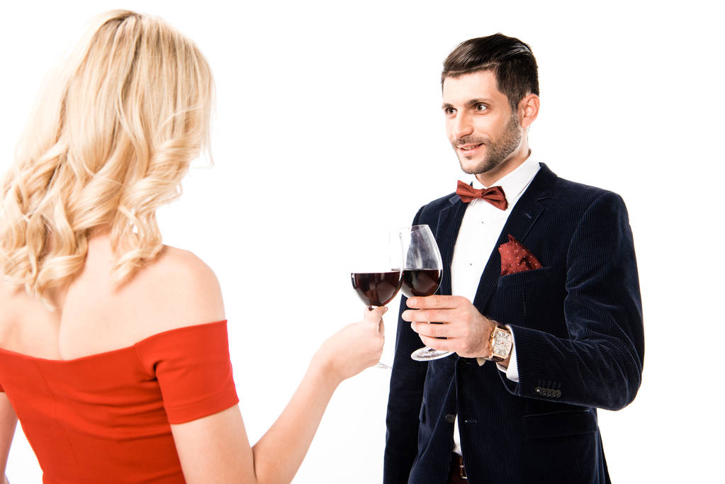 Обратный вид женщины в красивом красном платье и мужчина с бокалами красного вина изолированы на белом
 - Фото, изображение
