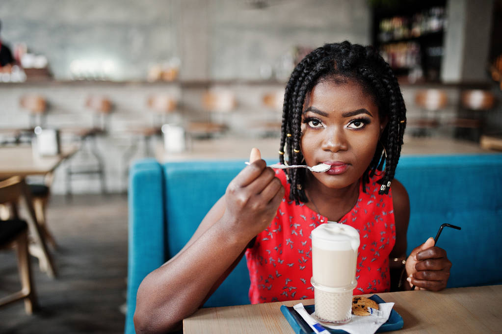 Belle femme afro-américaine assise à table sur un café avec latte
. - Photo, image