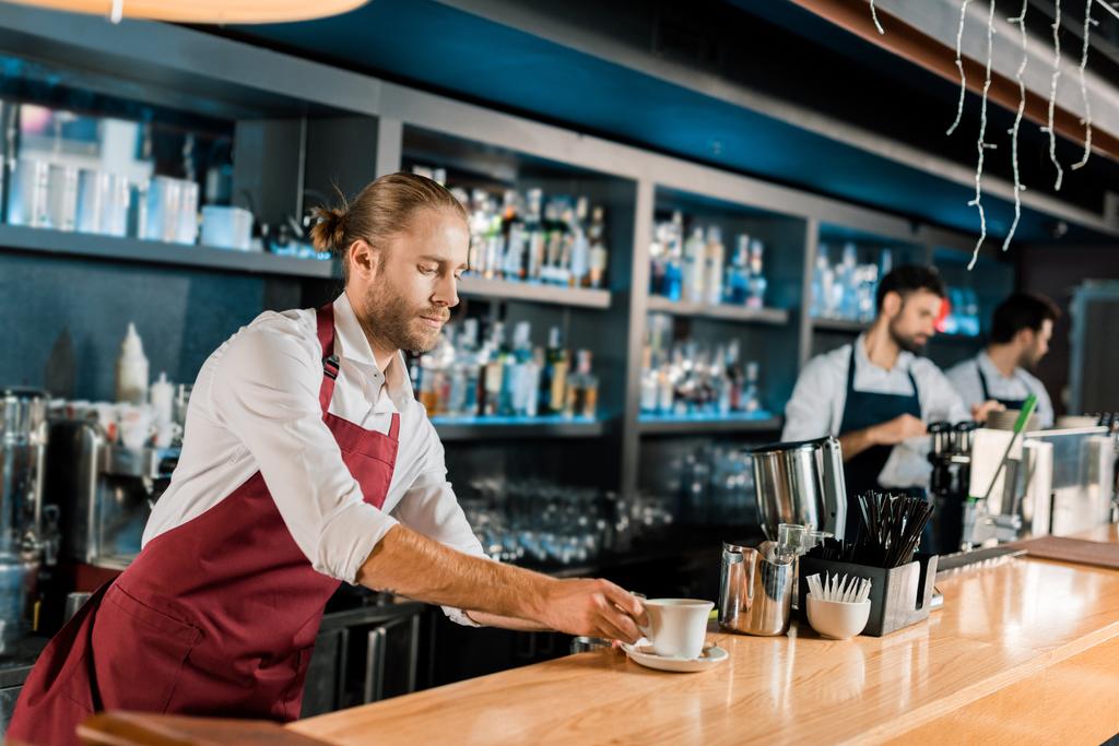yakışıklı barista kahve servisi ahşap kasada önlük - Fotoğraf, Görsel