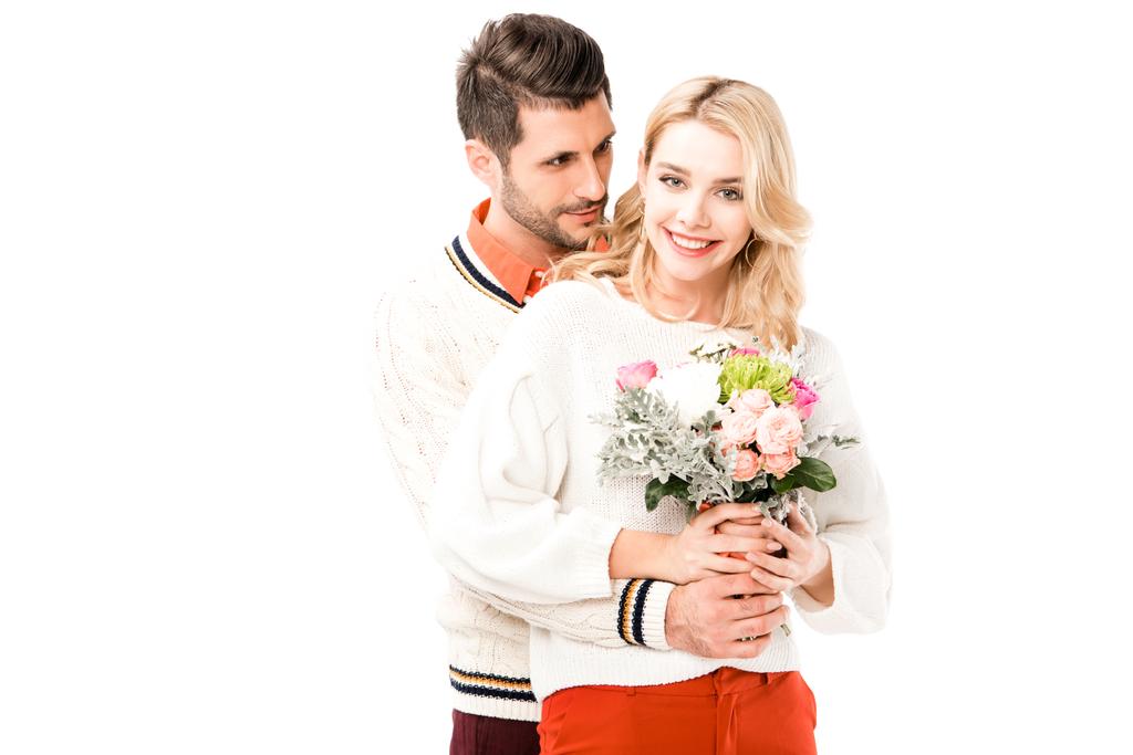 Όμορφος άνδρας αγκαλιάζει όμορφα girlfiend με λουλούδια που απομονώνονται σε λευκό - Φωτογραφία, εικόνα
