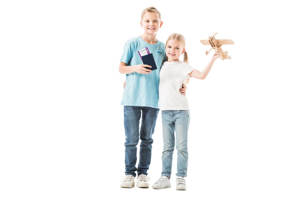 Sorella e fratello in piedi con passaporto e modello aereo isolato su bianco
 - Foto, immagini