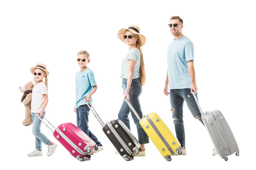 Família feliz andando com bagagem colorida e sorrindo isolado no branco
 - Foto, Imagem