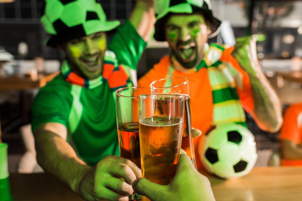 Cheering football fans clinking glasses of beer in bar - Photo, Image