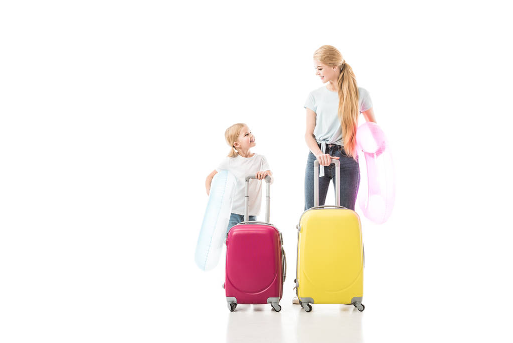 Madre e hija sonriendo y sosteniendo el equipaje aislado en blanco
 - Foto, imagen