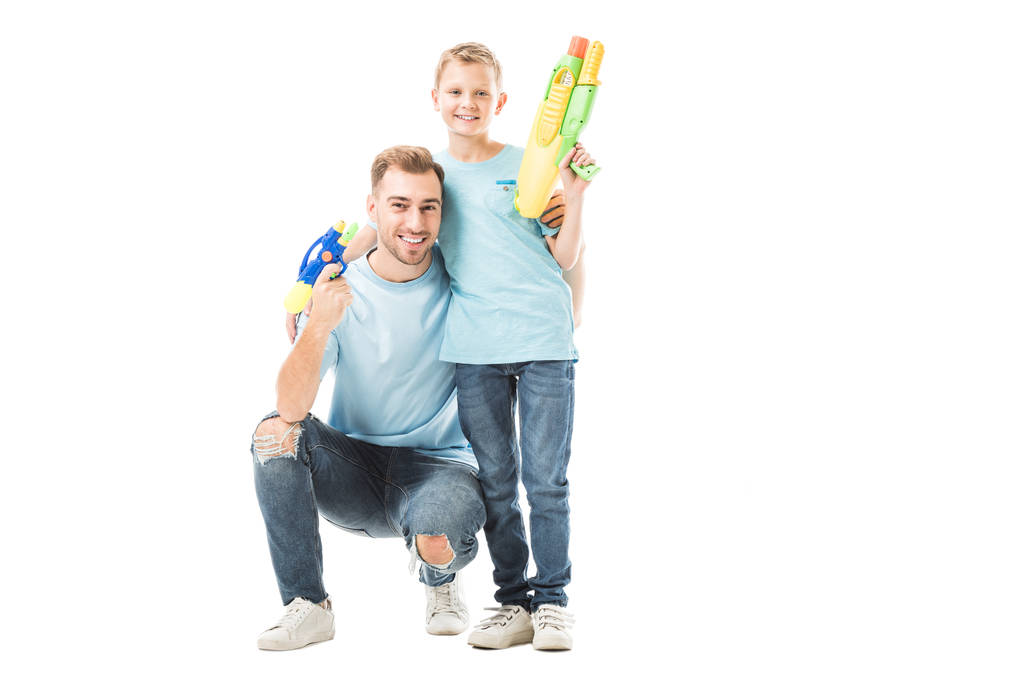 Папа и сын держат водяные пистолеты и улыбаются изолированно на белом
 - Фото, изображение
