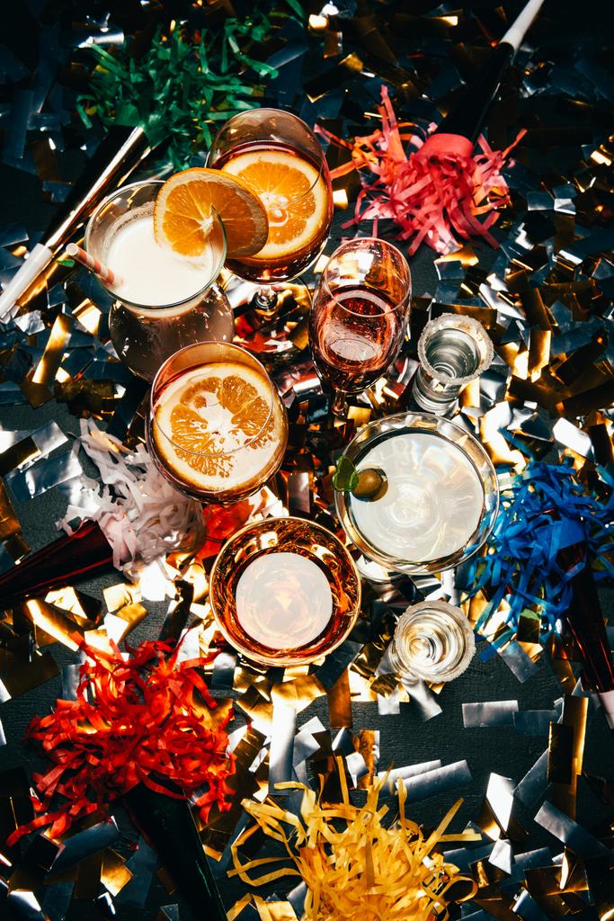 pohled shora různých alkoholických koktejlů a strana rohy na tabulka překrytá zlaté konfety  - Fotografie, Obrázek