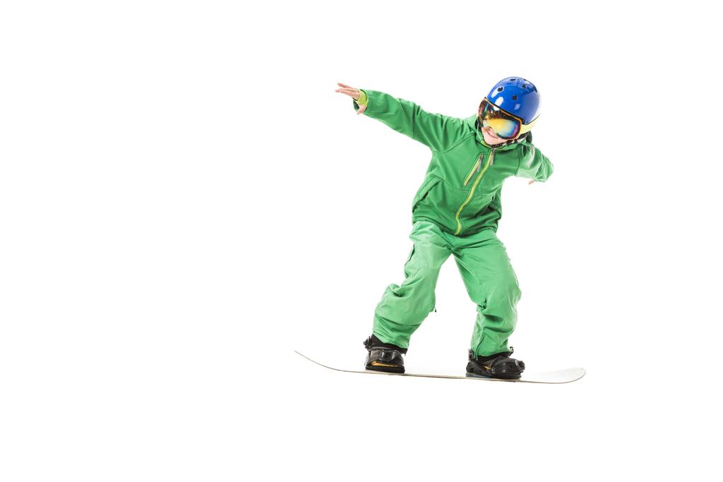 preteen boy in green ski suit, goggles and blue helmet snowboarding isolated on white - Photo, Image