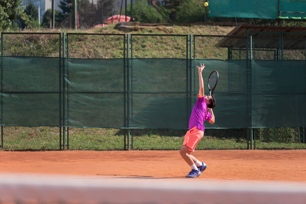 Nuori tennispelaaja palvelee palloa
 - Valokuva, kuva