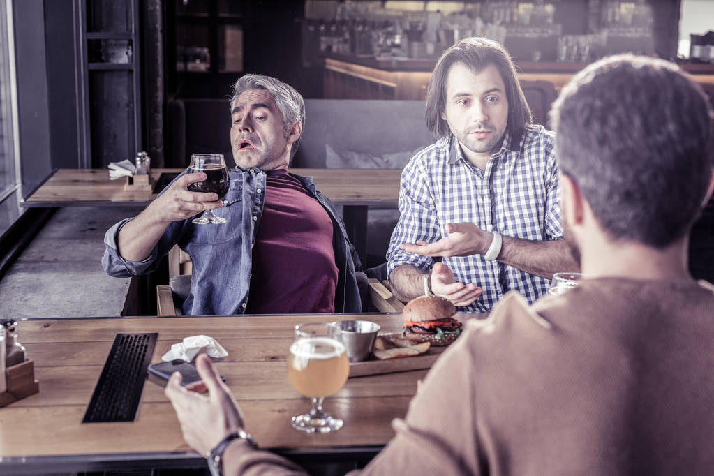 Frustrierte männliche Person starrt Bocal mit Bier an - Foto, Bild