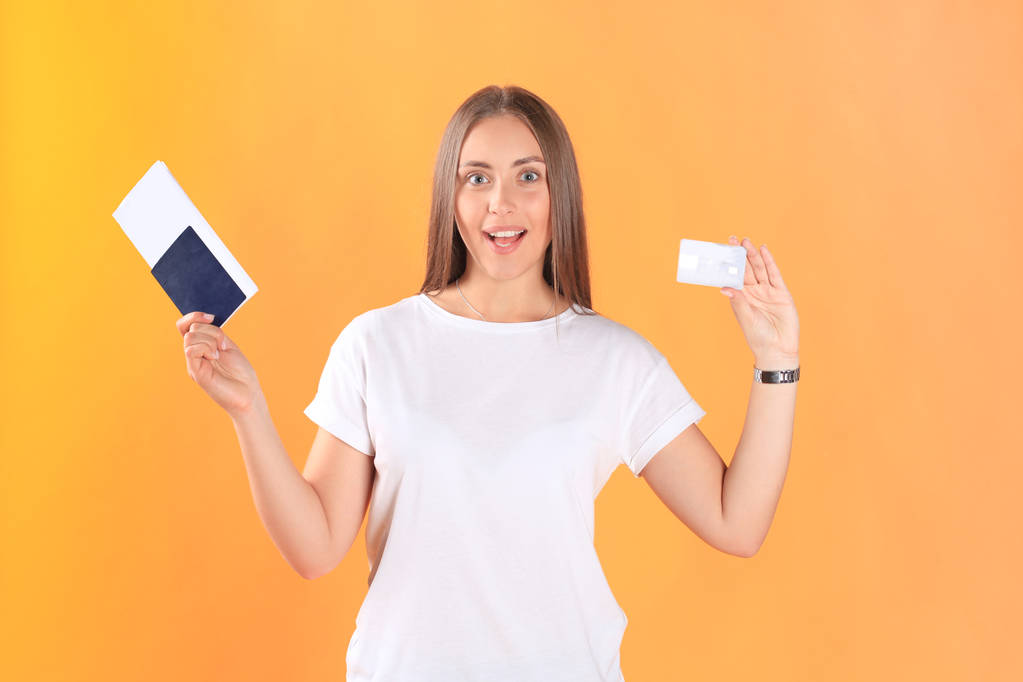 興奮した若い女性観光航空券、プラスチック製のクレジット カードとパスポートを保持しての分離の黄色の背景に立っています。. - 写真・画像
