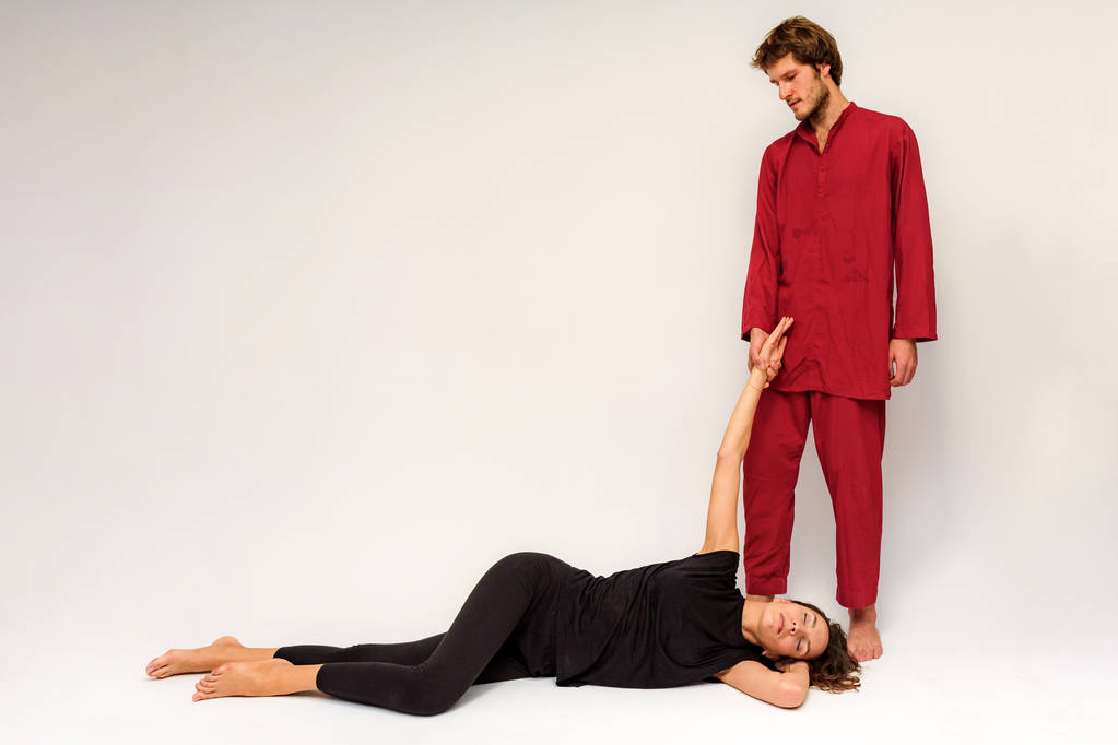 Foto de poses de ioga no chão para dois alongamento e relaxamento em um fundo branco. O homem estende a mulher bem na frente da câmera
. - Foto, Imagem