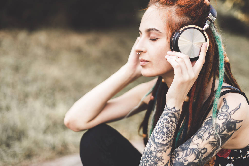 jovem com tatuagem e dreadlocks ouvir música no parque
 - Foto, Imagem