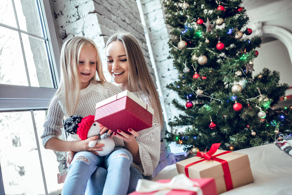 anya és lánya közelében karácsonyfa nevetve ajándékokkal. - Fotó, kép