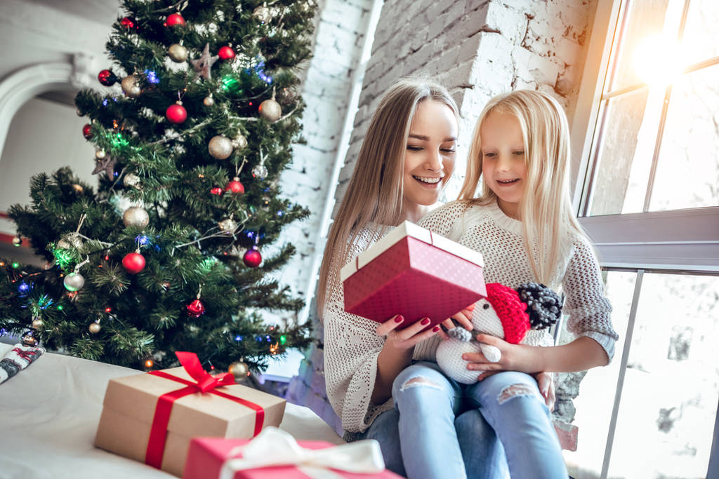 madre e hija con regalos cerca del árbol de Navidad riendo
. - Foto, imagen