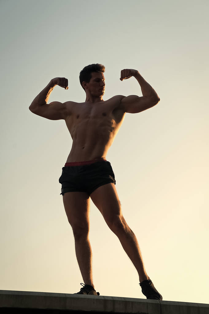 Man showing fit body on blue sky - Photo, Image