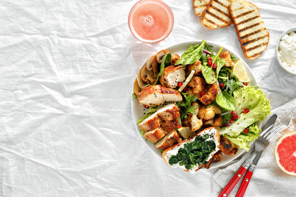 Lunchfutterschale mit frischem Salat mit Hickensteak und gebratenem Blumenkohl auf weißem Hintergrund mit frischer Draufsicht auf Grapefruit. Kopierraum. gesundes Ernährungskonzept - Foto, Bild