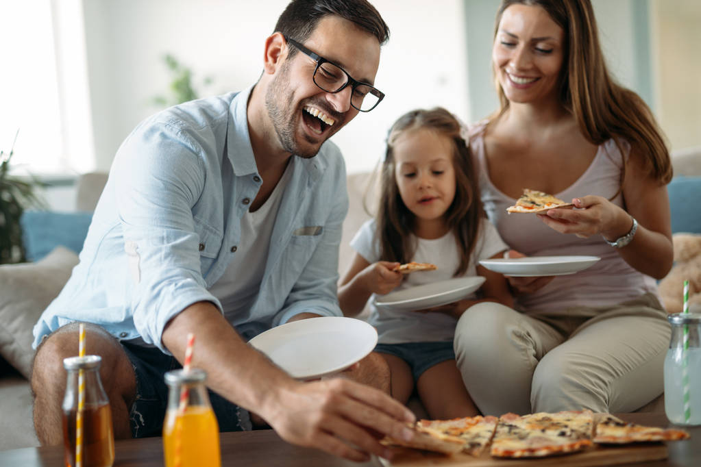 Retrato de familia feliz compartiendo pizza juntos en casa
 - Foto, Imagen