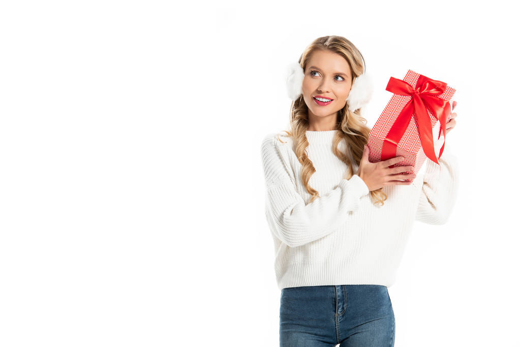 glückliches Mädchen im Winter-Outfit hält Weihnachtsgeschenk-Box isoliert auf weiß - Foto, Bild