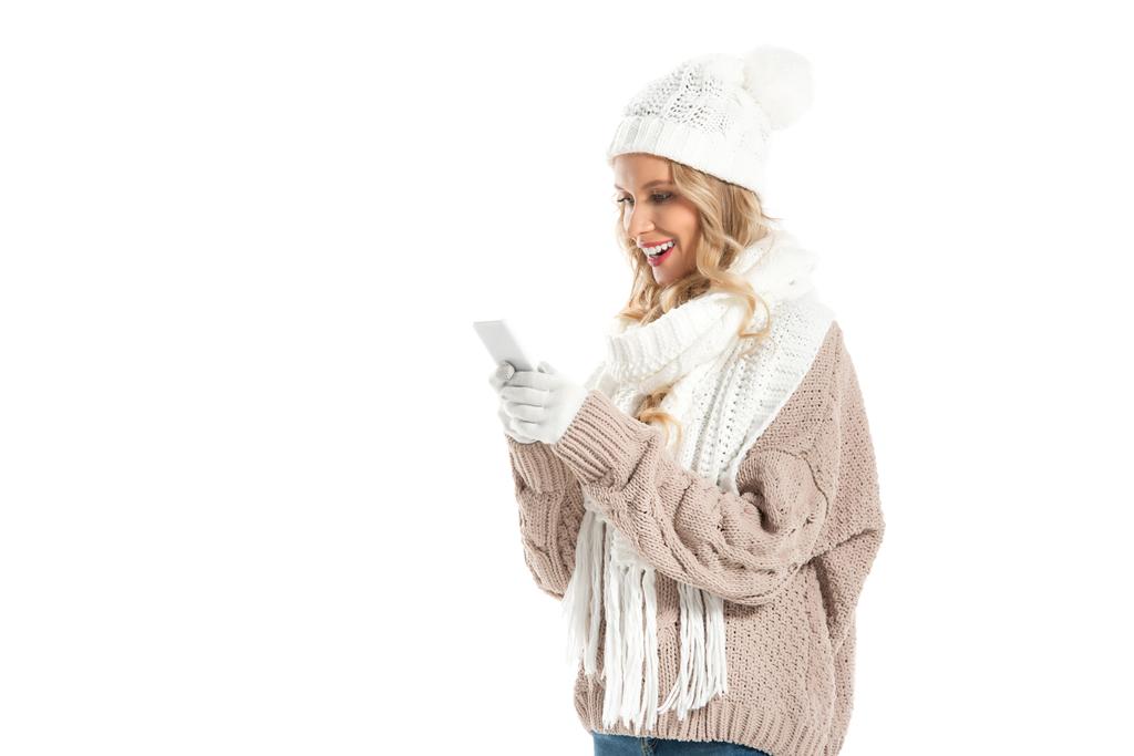 schöne lächelnde Frau in Wintermütze und Schal mit Smartphone isoliert auf weiß - Foto, Bild