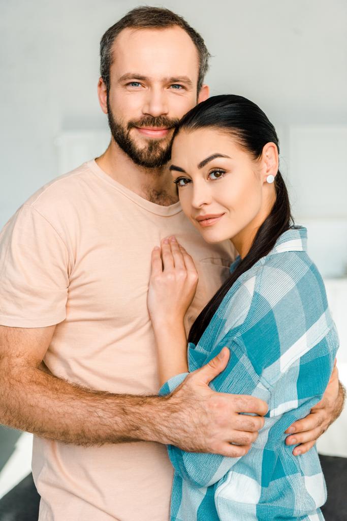 Porträt eines glücklichen Paares, das sich umarmt und in die Kamera blickt  - Foto, Bild