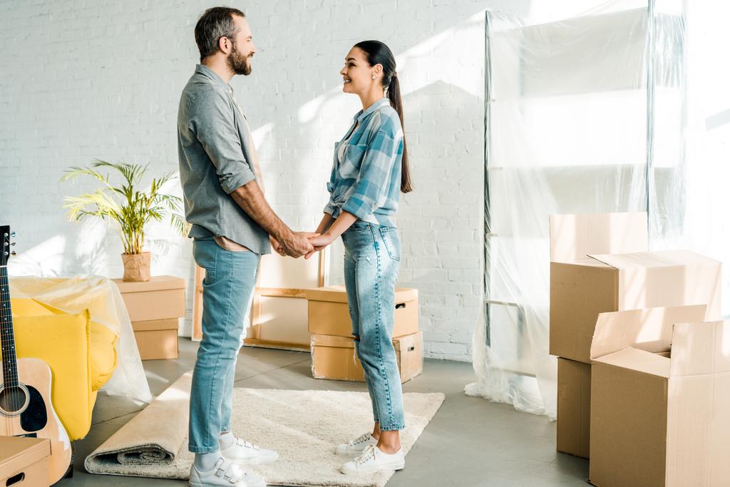 Aufgeregtes Paar hält Händchen beim Packen für neues Haus, Umzugskonzept - Foto, Bild