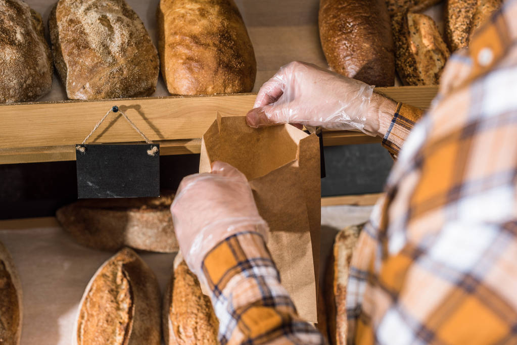 oříznutý pohled na mužské ruce dát chleba do papírového sáčku - Fotografie, Obrázek