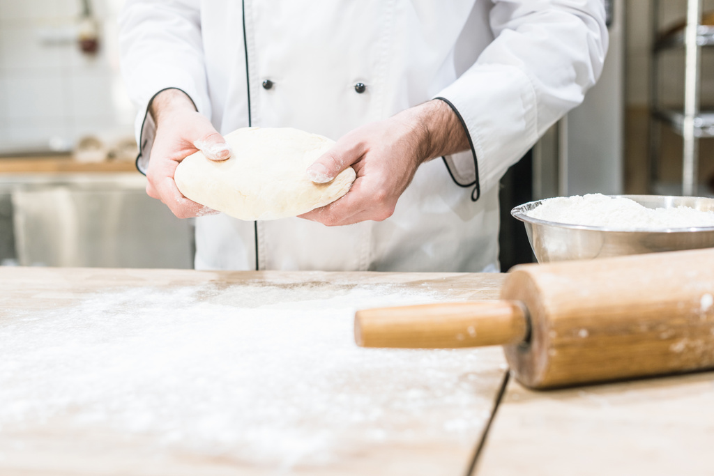 Пекарь держит в руках сырое тесто
  - Фото, изображение