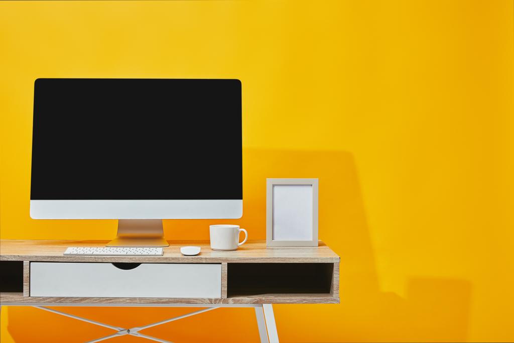 コンピューター、黄色の木のテーブルで、コーヒーと写真フレームのカップ  - 写真・画像