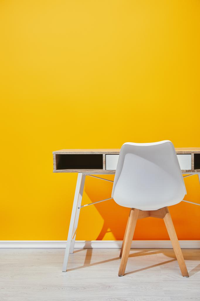 Дерев'яний стіл з білим стільцем гірше жовта стіна
 - Фото, зображення