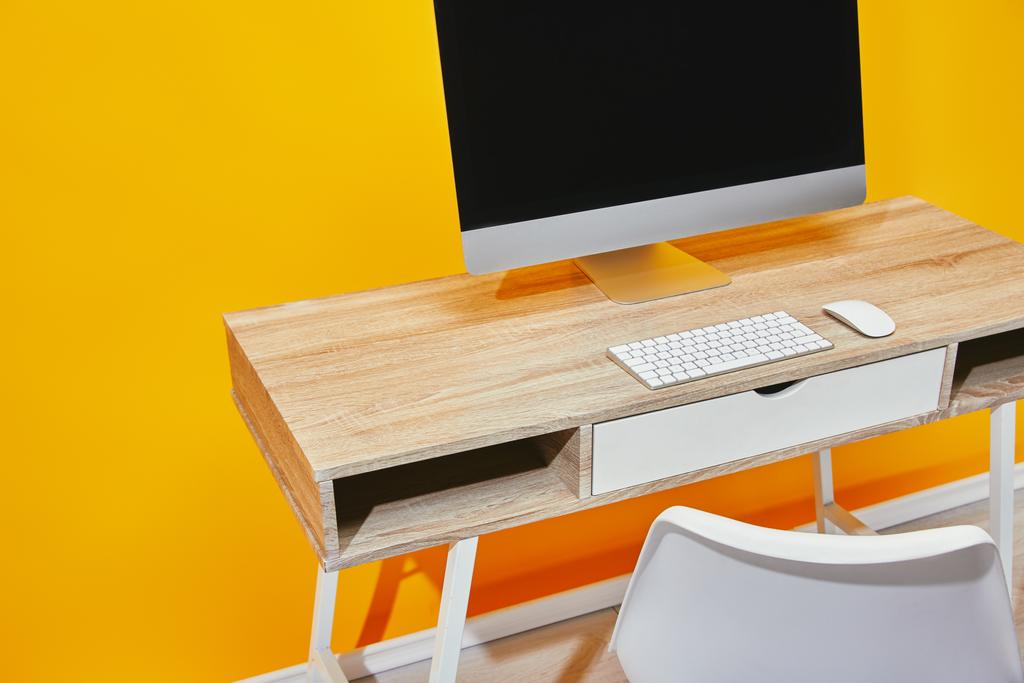 close up of workplace with computer and wooden table near yellow wall - Photo, Image