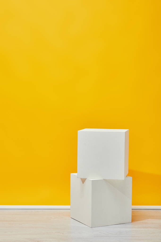 δύο γύψος κύβους κάθετα τοποθετημένα κοντά σε κίτρινο τοίχο - Φωτογραφία, εικόνα
