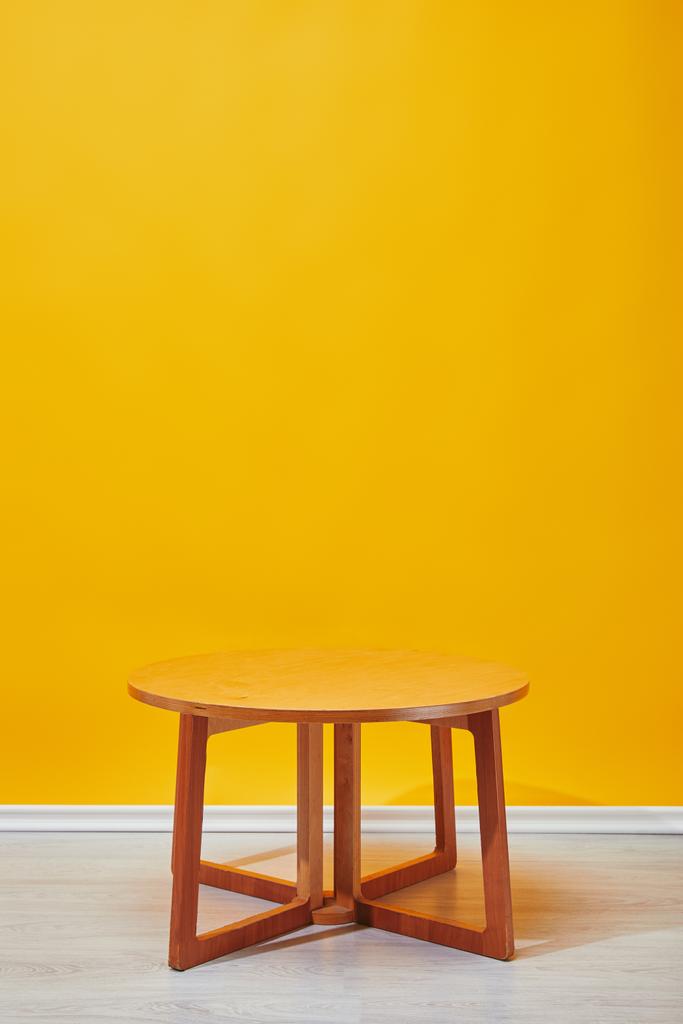 背景に黄色の壁と小さな木製のコーヒー テーブル  - 写真・画像