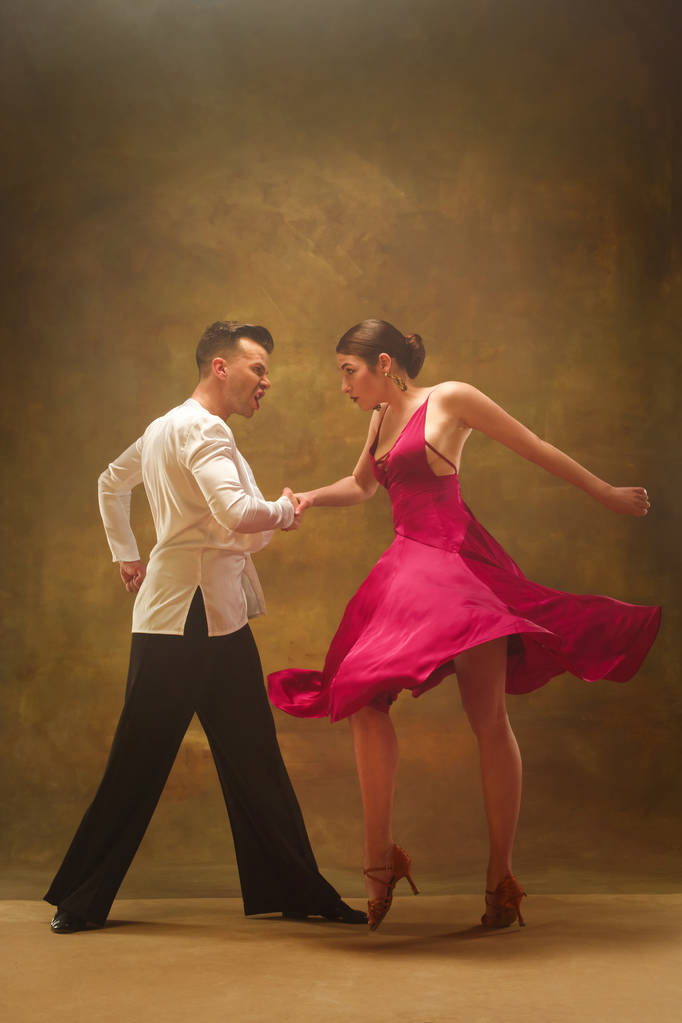 Tańca towarzyskiego para w złota sukienka taniec na tle studio. - Zdjęcie, obraz