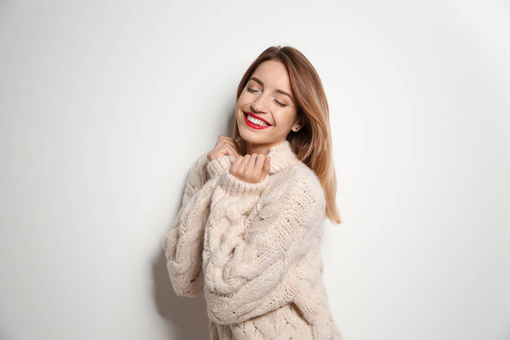 Όμορφη νεαρή γυναίκα σε ζεστό πουλόβερ σε λευκό φόντο - Φωτογραφία, εικόνα