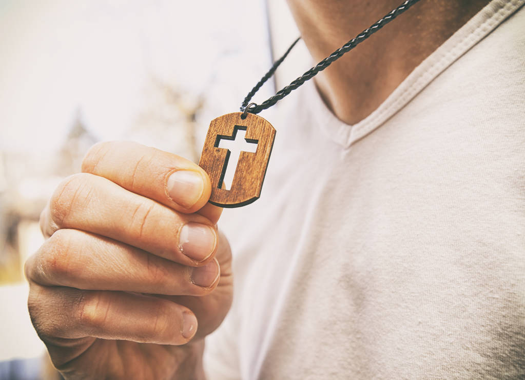 Дерев'яне намисто хреста на шиї людини
 - Фото, зображення