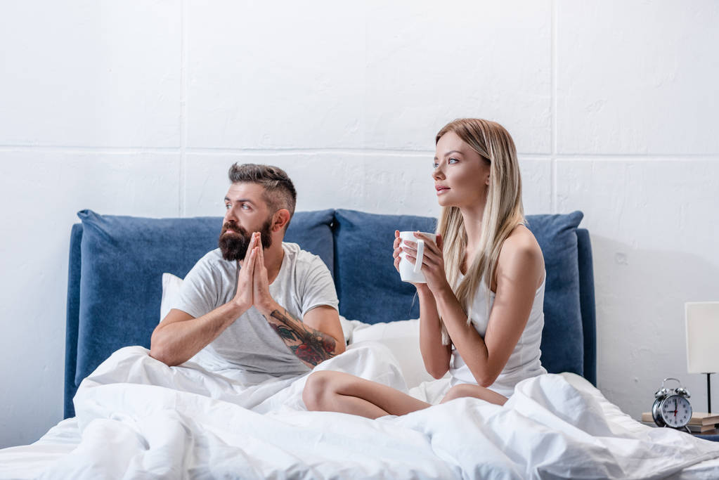 Jong koppel drinken koffie in witte bed in de ochtend - Foto, afbeelding