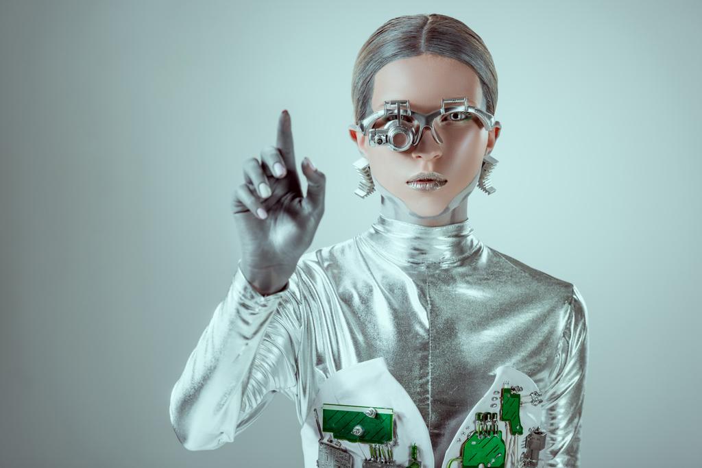 futuristische zilveren cyborg gebaren met hand en kijken naar camera geïsoleerd op grijs, toekomstige technologie concept   - Foto, afbeelding