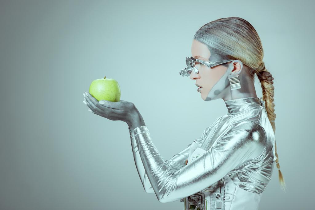 vista laterale della tenuta cyborg ed esame mela verde isolata su grigio, concetto tecnologico futuro
  - Foto, immagini