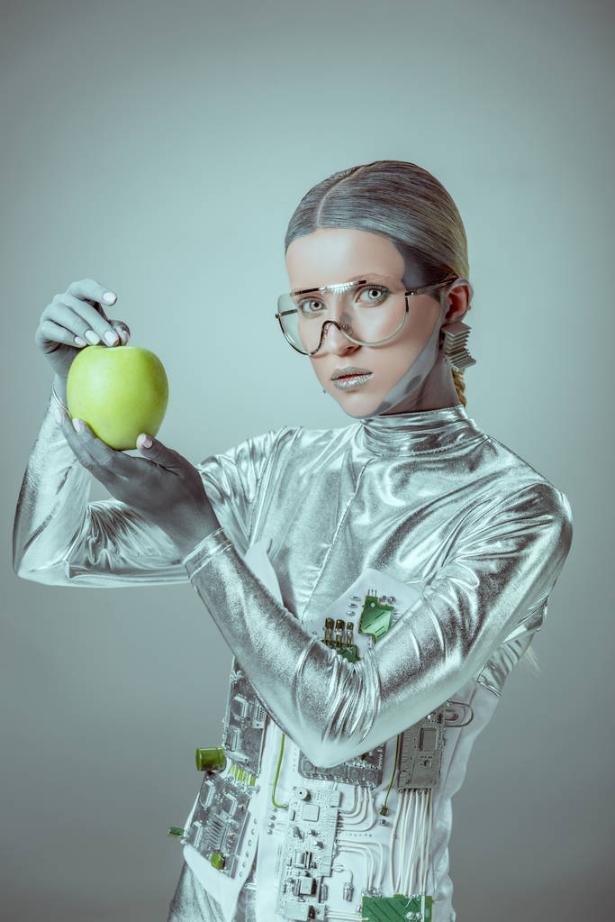 робот в футуристических очках, держащий яблоко и смотрящий на камеру, изолированную на серой, будущей технологической концепции
  - Фото, изображение