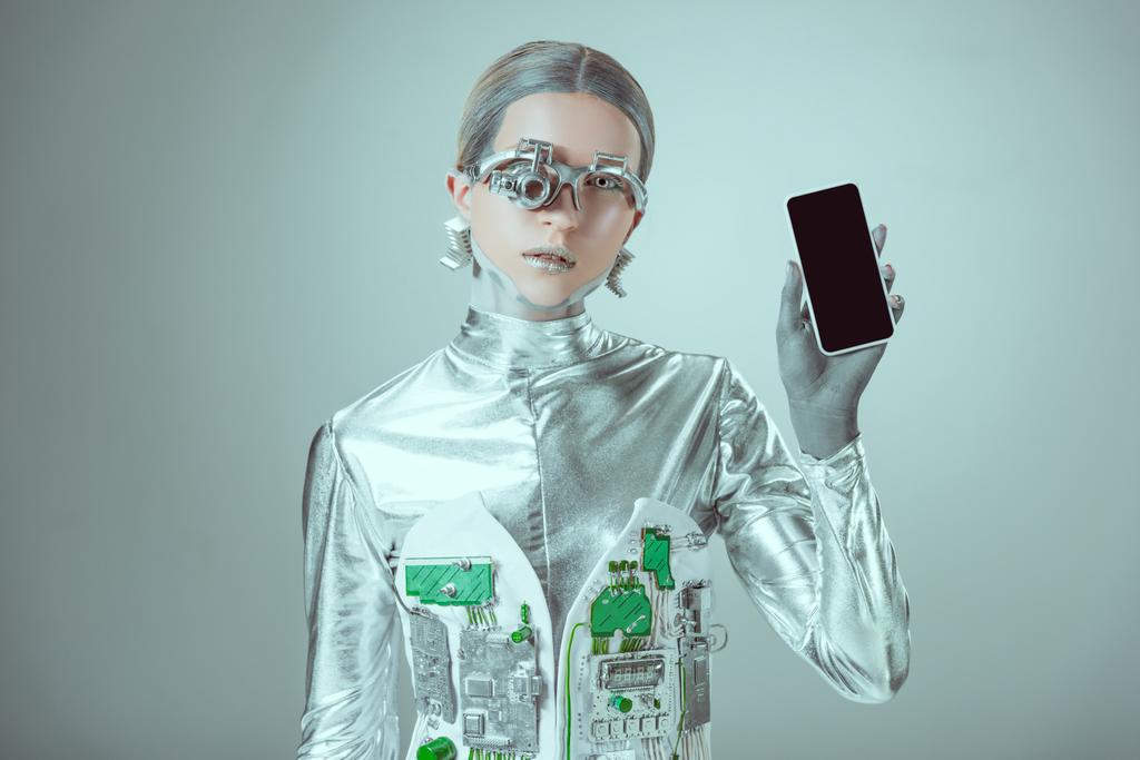 robot que sostiene el teléfono inteligente con la pantalla en blanco y mirando a la cámara aislada en gris, el concepto de tecnología futura
    - Foto, imagen