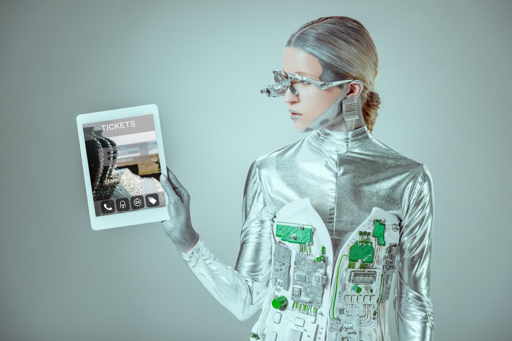 Silberroboter blickt auf Tablet mit Fahrkartengerät isoliert auf graues, zukünftiges Technologiekonzept - Foto, Bild