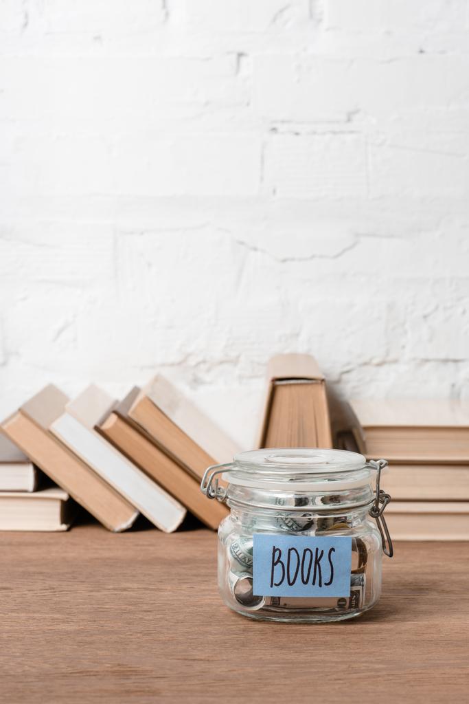 zbliżenie słoik z oszczędności i napis książek na drewnianym stole - Zdjęcie, obraz
